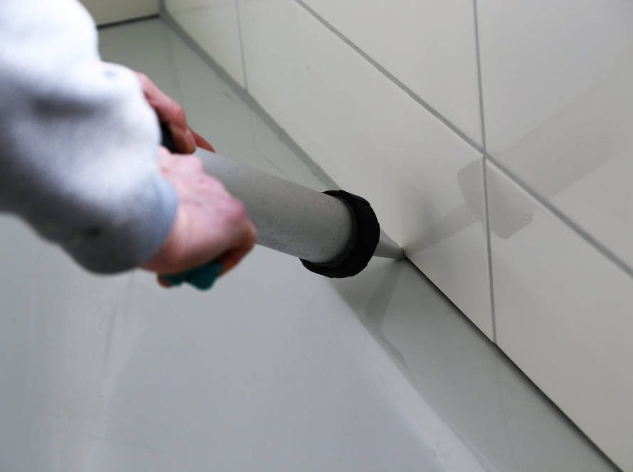 grout and calking technician applying new calk to bathroom