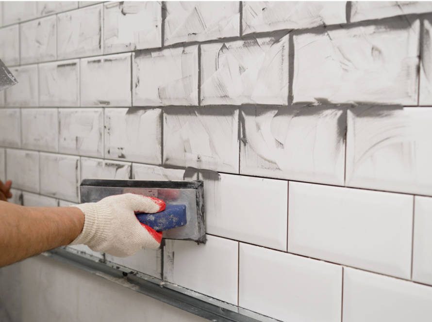 tile and grout specialist applying new grout to newly installed wall tiles